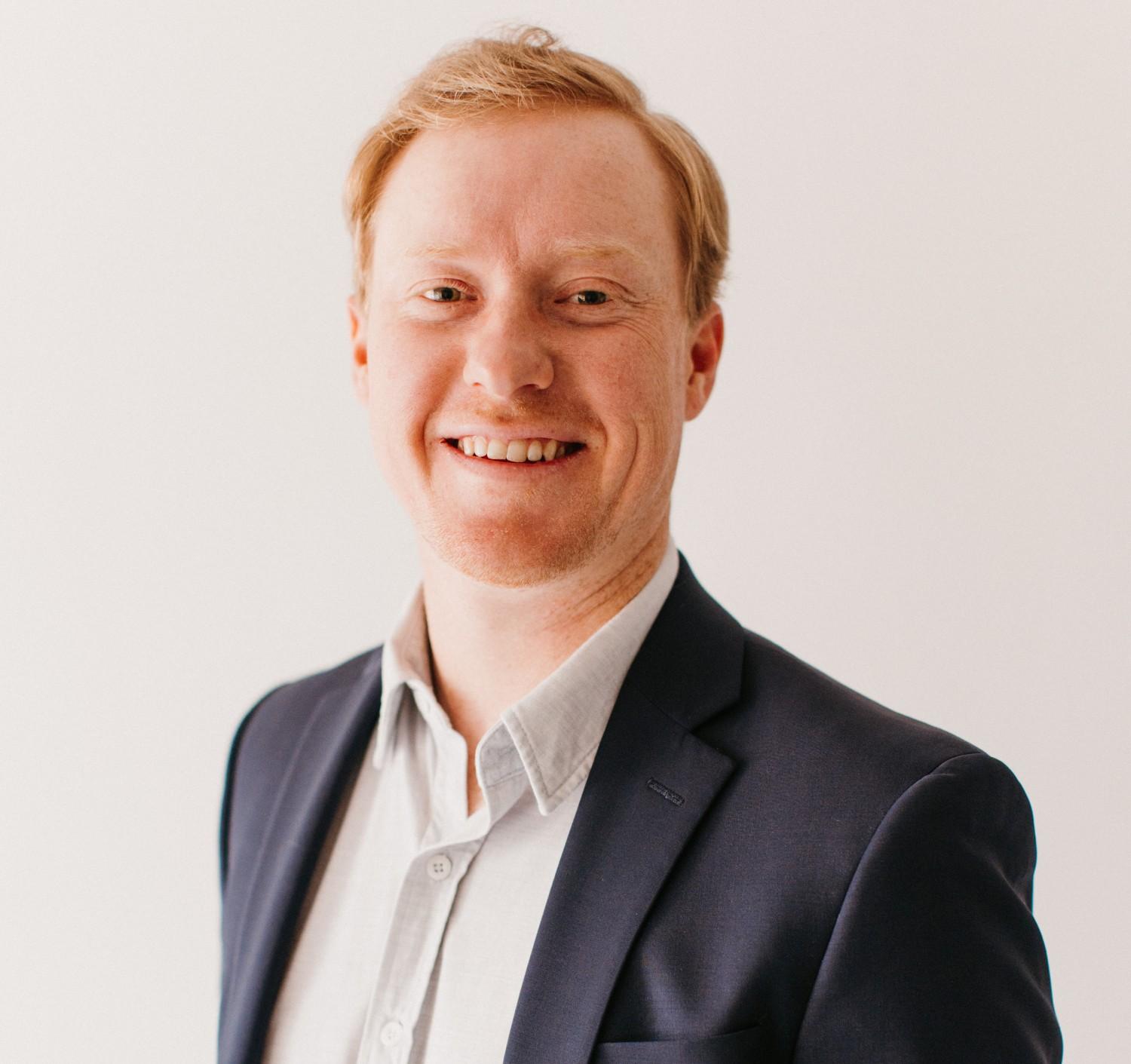 Picture of Mike Holtz, CFP® and financial advisor at Toberman Becker Wealth. Mike is wearing a collared white shirt under a black blazer and is smiling at the camera.